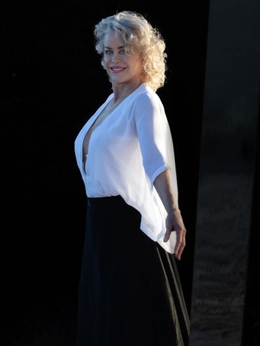 Woman in white blouse and black skirt smiling.