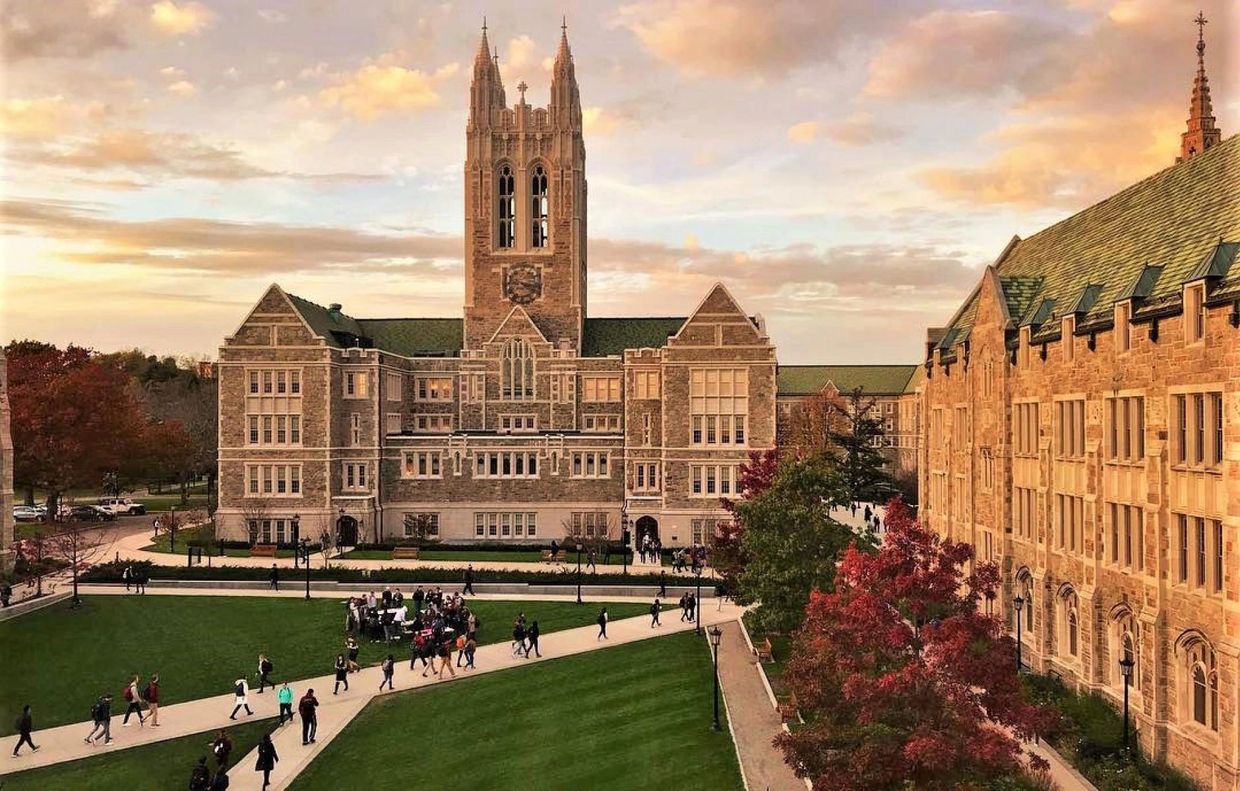 Historic university campus with students and autumn trees at sunset.