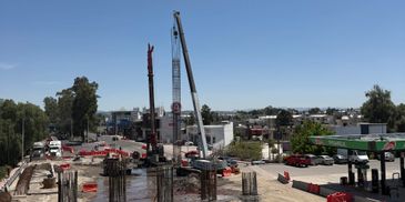 Busy construction site with cranes and concrete pillars under clear sky.