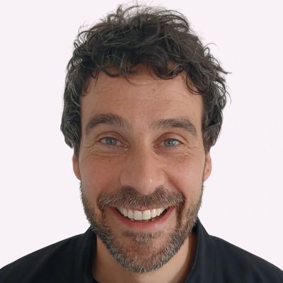 Smiling man with curly hair and beard.