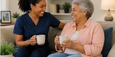 A nurse and elderly woman share a joyful moment with coffee.