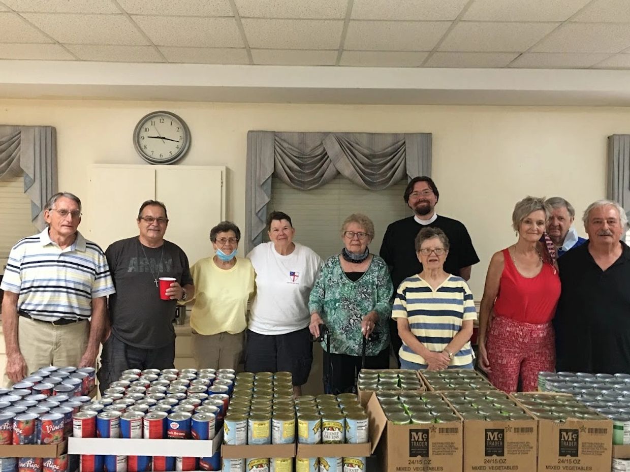 Group of people smiling while standing over food to be distributed to the needy.