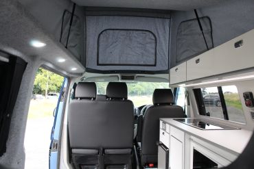 Interior of a camper van with folded-down overhead bed.