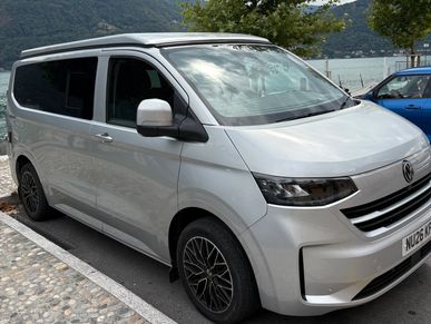 Silver Volkswagen van parked near a lake.