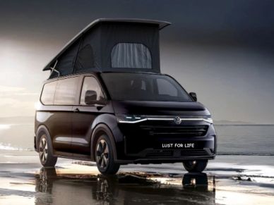 Black Volkswagen camper van with roof tent near water.