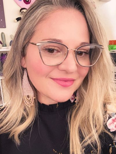 Casey Murphy has blonde hair and is wearing glasses, smiling. Roller skate art is in the background.