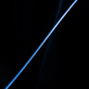 Close-up of a serrated blade edge glowing blue in dark.
