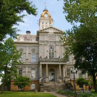 Historic courthouse building surrounded by green trees under a clear sky.