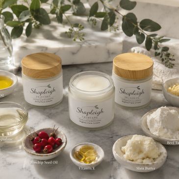 Shapleigh Skincare creams surrounded by natural ingredients like oils, butters, and beeswax.
