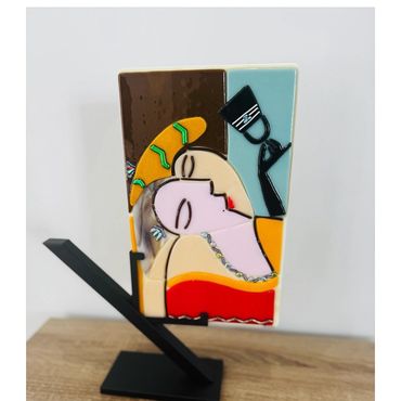 Abstract art sculpture of a reclining figure with a drink, vibrant colors.