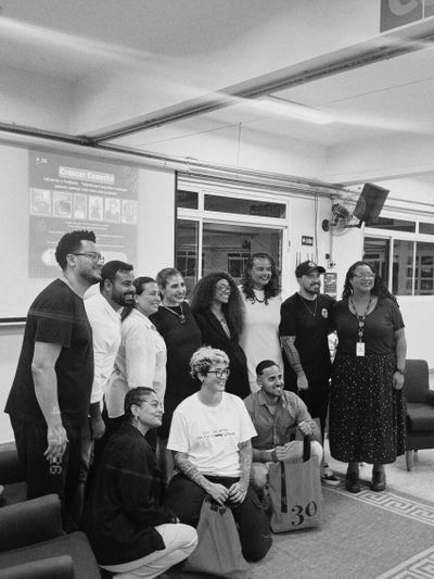 Group photo of diverse people smiling indoors, some seated and some standing.