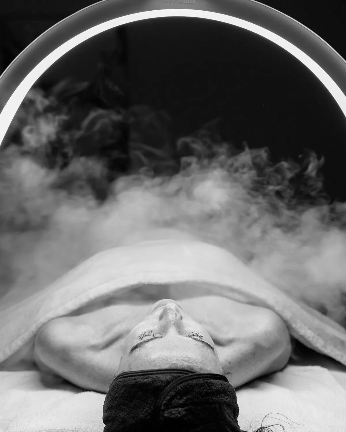 Person wrapped in towel with steam or vapor around.