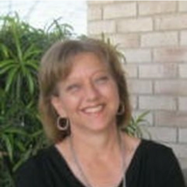 Smiling woman with short hair wearing hoop earrings outdoors.