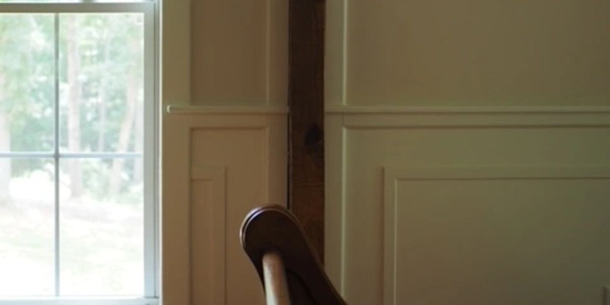 Chair by window with beige wall paneling and natural light.