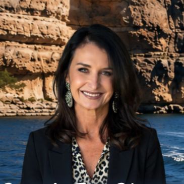Woman smiling in front of rocky cliffs and water.