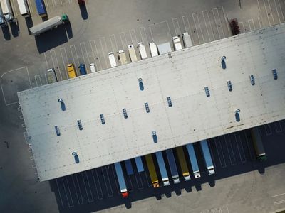 Aerial view of trucks parked around a large warehouse with empty parking spaces.