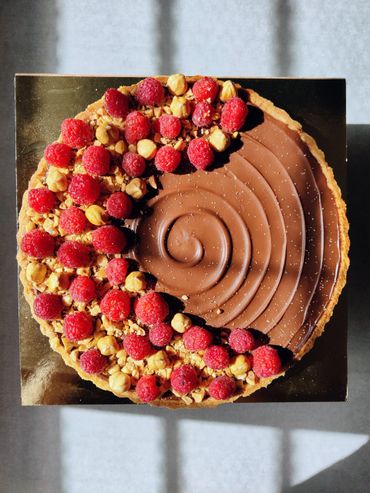 Chocolate tart topped with fresh raspberries and nuts.