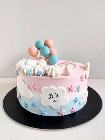 A pastel pink and blue cake decorated with stars, clouds, and balloons.