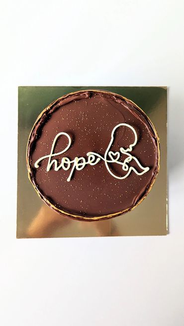 Chocolate cake with 'hope' and a baby outline in white icing.