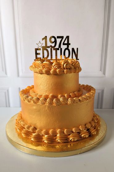 Elegant two-tier golden cake with '1974 EDITION' topper.