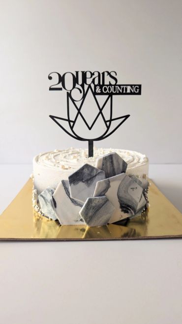 Elegant white cake with marble geometric decorations and 20 years celebration topper.