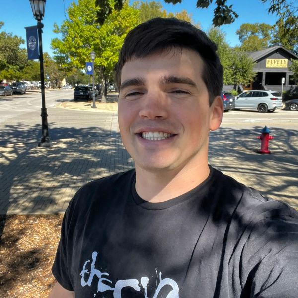 Young man smiling outdoors on a sunny day.
