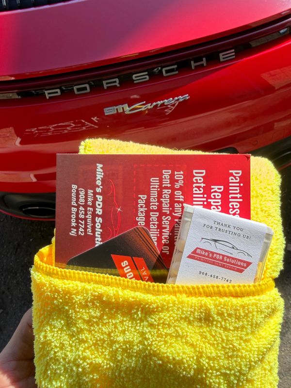 Pamphlets and cards in a yellow cloth in front of a red Porsche 911 Carrera.