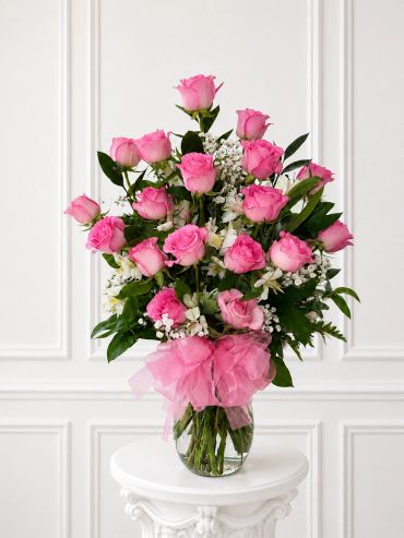 Elegant bouquet of pink roses in a vase with white flowers and greenery.