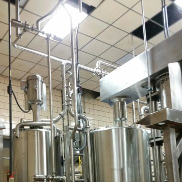 Industrial stainless steel tanks and pipes in a factory setting.