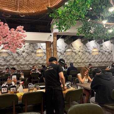 Cozy restaurant interior with diners and decorative greenery.