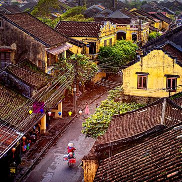 A vibrant street scene in an old town with tiled roofs and colorful lanterns.