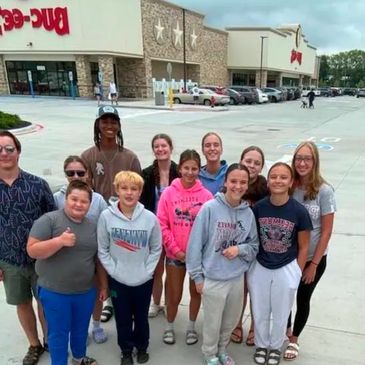 Group of people posing outside a shopping center.