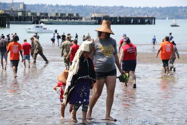 A pregnant paddler leads her children away from the shore during Canoe Journey.