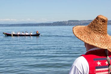 A Native veteran watches a canoe in the distance at Owen Beach.