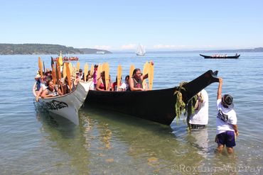 Canoe Journey volunteers help bring a canoe onto shore at Owen Beach in Tacoma.