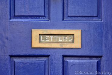 A blue door has a mailbox with the word “letters”.