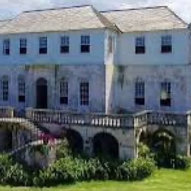 Historic white stone mansion with arched windows and a garden.