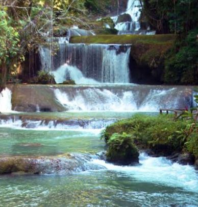 A serene multi-tiered waterfall flowing through lush greenery.