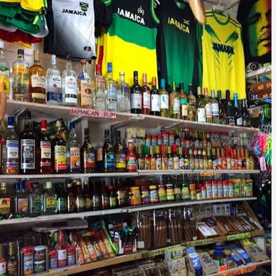 Shelves stocked with Jamaican rum, spices, and souvenirs under Jamaica-themed shirts.