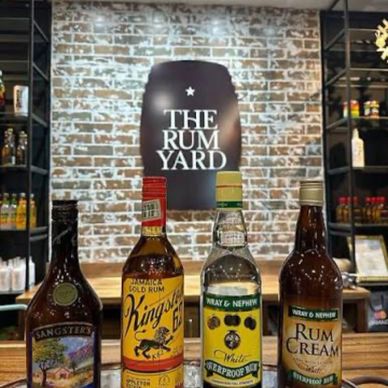 Four bottles of rum displayed in front of a brick wall with 'The Rum Yard' sign.