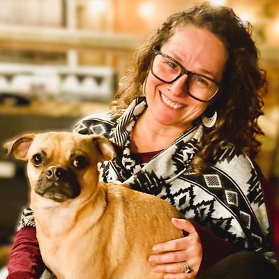 A woman smiling with a small dog on her lap.