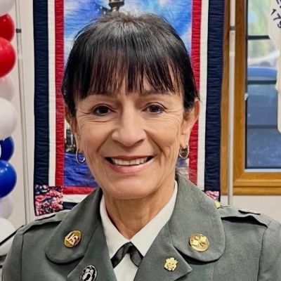 Woman in military uniform smiling indoors.