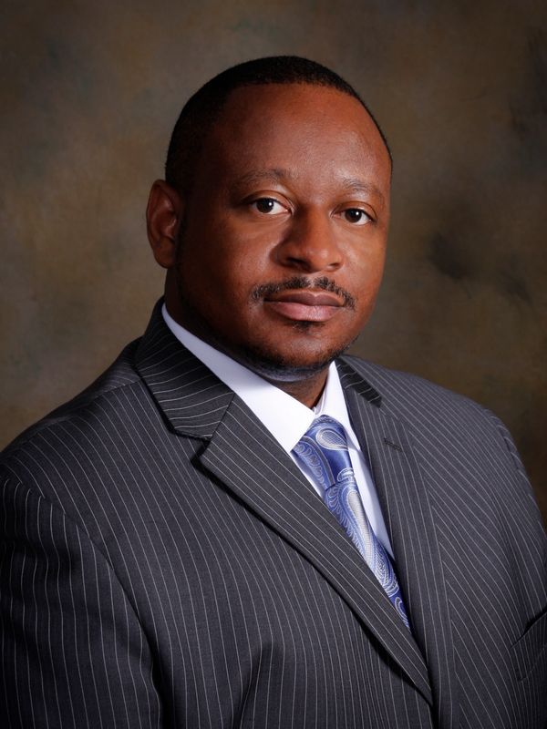 Professional man in pinstripe suit and patterned blue tie.