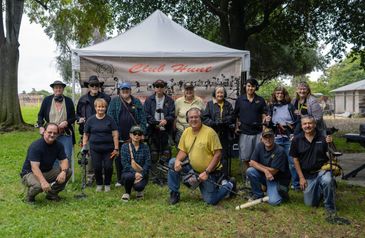 Group of people posing in front of a tent at an outdoor event.