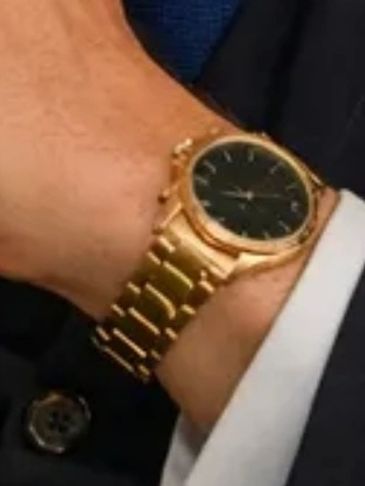 Elegant gold wristwatch with a black dial on a person's wrist.