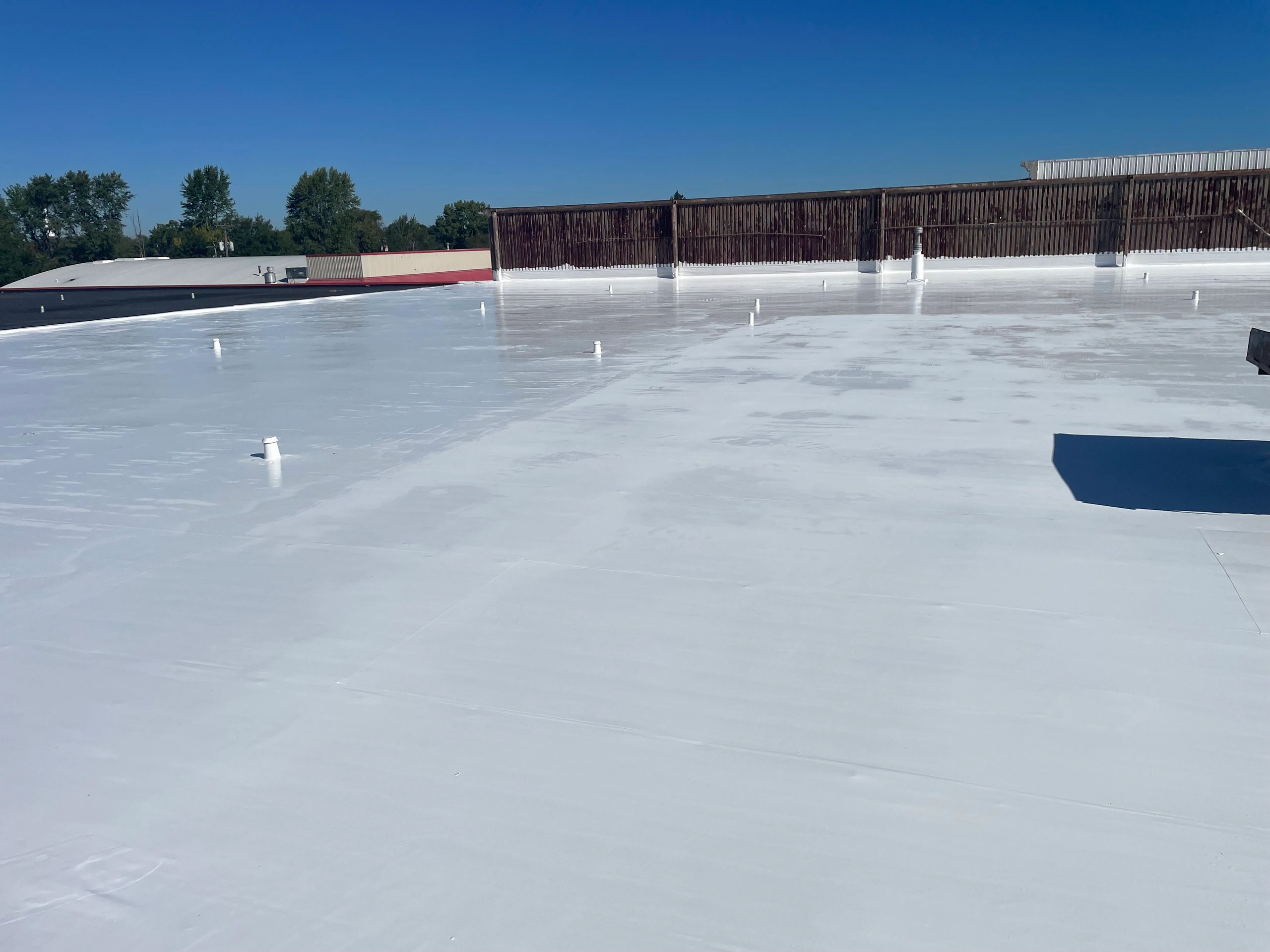 Newly coated white flat roof under clear blue sky.