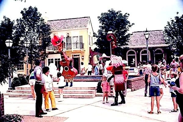 People enjoy an outdoor event with musicians in large costumes.