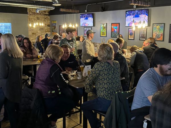 a crowd of people sitting inside TAQ Brewery