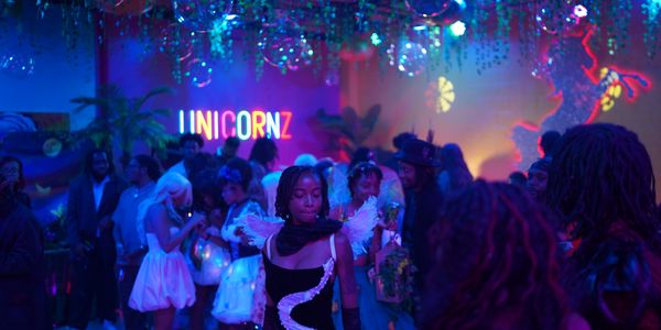 A vibrant party scene with colorful lighting and a neon unicorn sign.