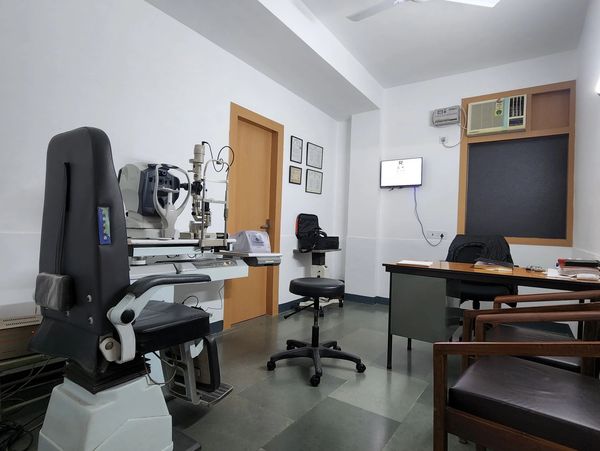 Empty eye clinic with ophthalmic equipment and chairs.